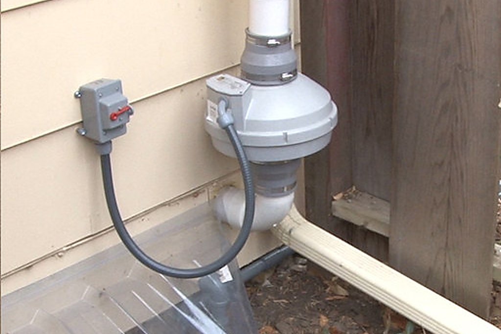 Exterior radon mitigation fan and vent pipe installed at a Mesa County home